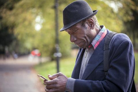 Older gentleman looking at smartphone in a park
