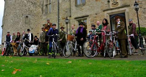 A group of baby boomers with their bikes. Some bikes have side-seats attached meaning they can hold a seated person as well as the rider. 