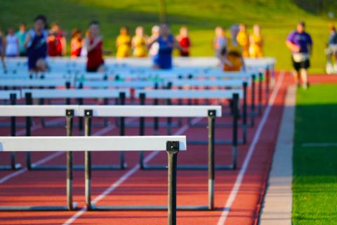photo of people in a race jumping hurdles