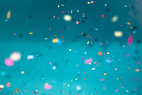 Colourful confetti falling down with a teal background