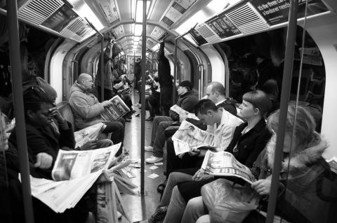 People reading newspapers on the London underground
