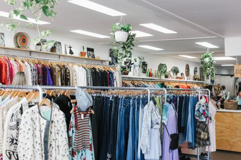 A charity shop interior, with many clothes hanging up