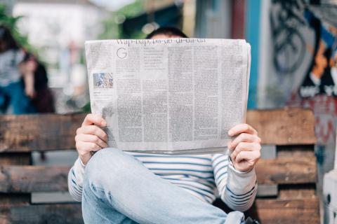 Man holds a newspaper in front of his face