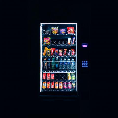 Lit up vending machine set against dark black background