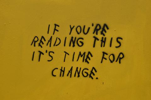 Black stencil graffiti text reading 'If you're reading this it's time for change' against a yellow background