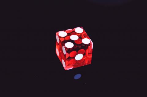 Red die showing number 4 against black background