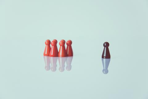 Group of plastic figures and one solitary plastic figure against a light blue background.