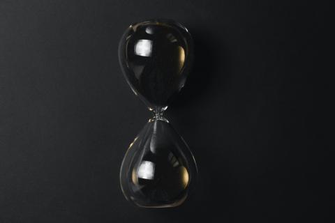 Transparent hourglass against dark grey background