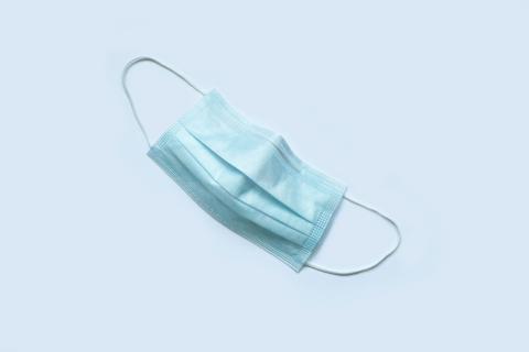 Blue medical facemask against a light blue background