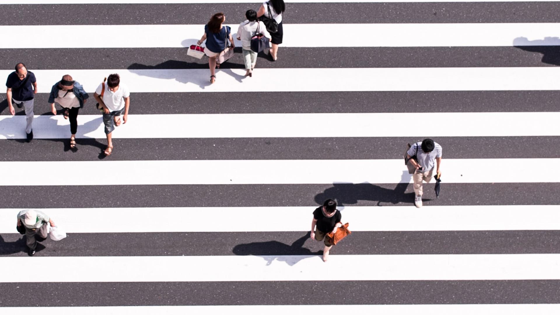 pedestrians walking across a zebra crossing from above