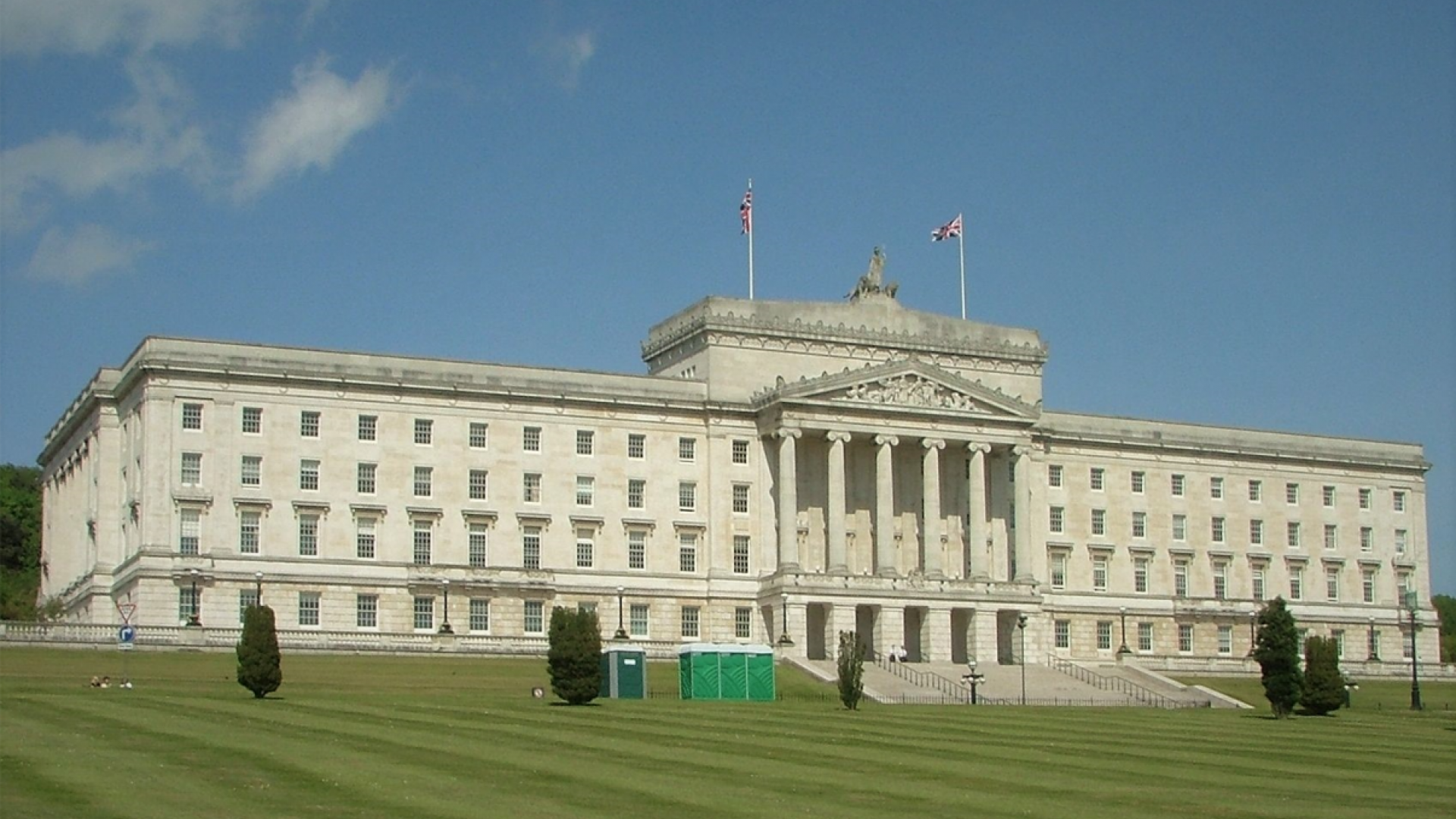 A stately white building with a rolling green lawn in front of it