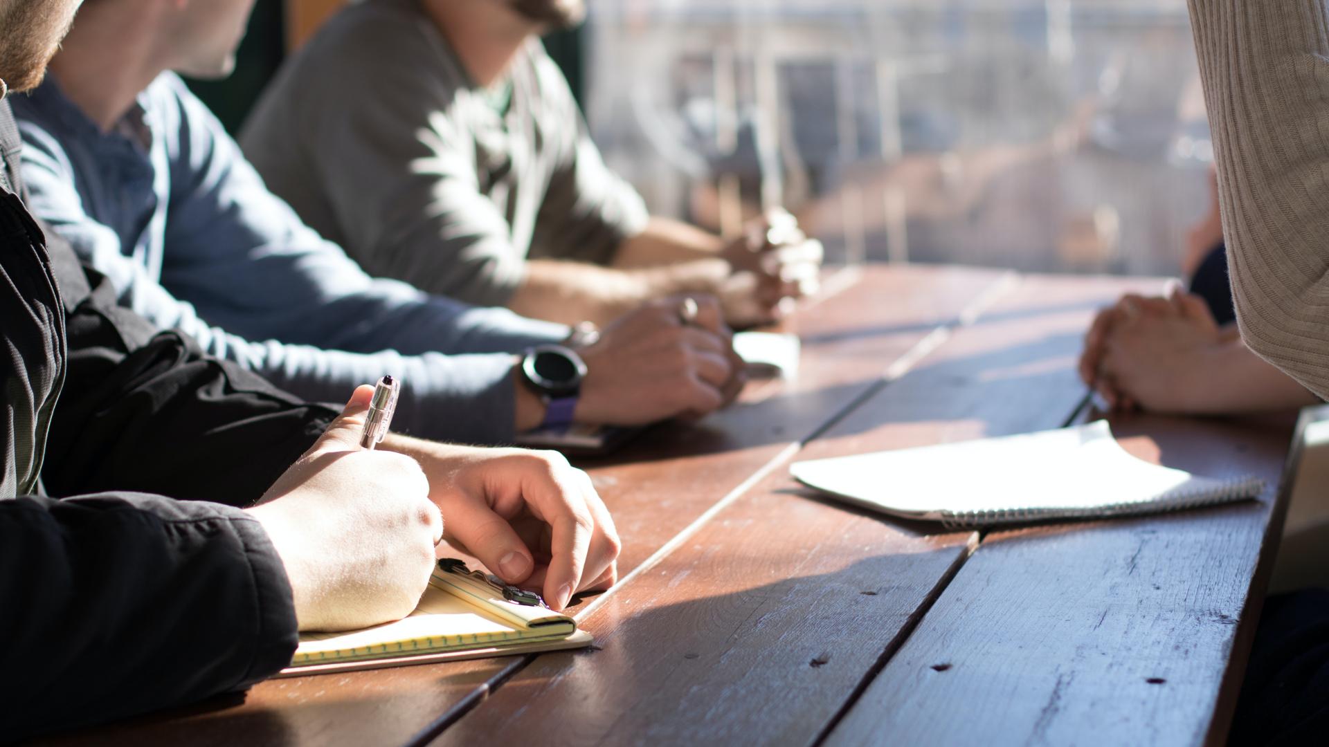 People having a discussion around a wooden table