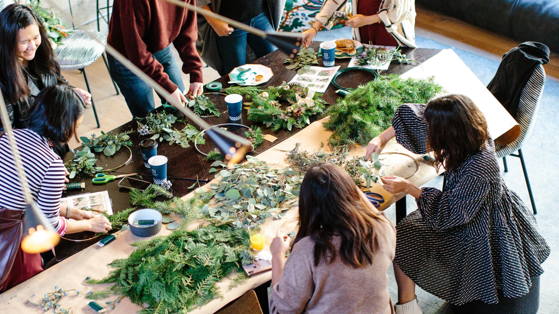 A group of people around a table, working with green vegetation