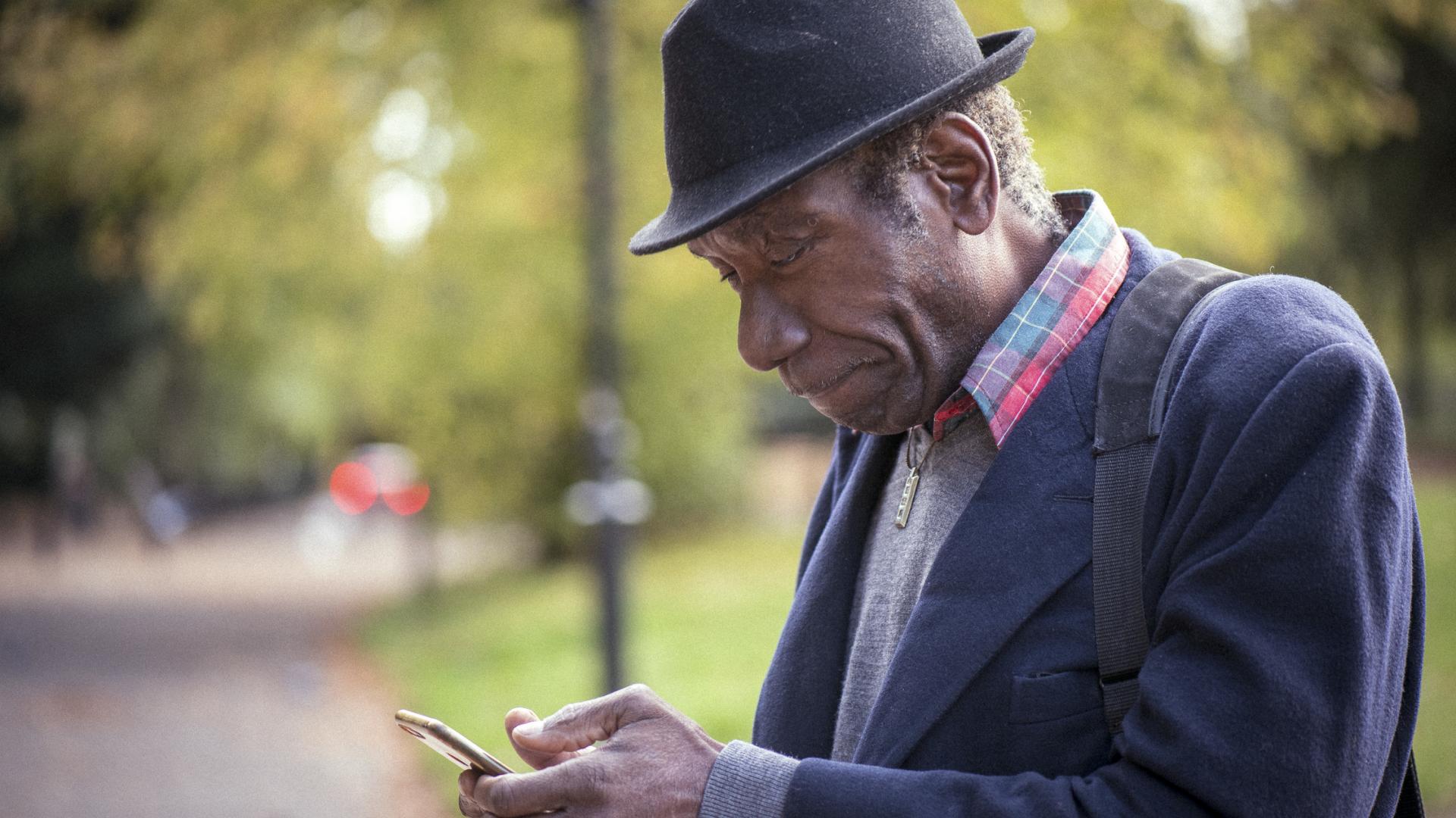 Older gentleman looking at smartphone in a park