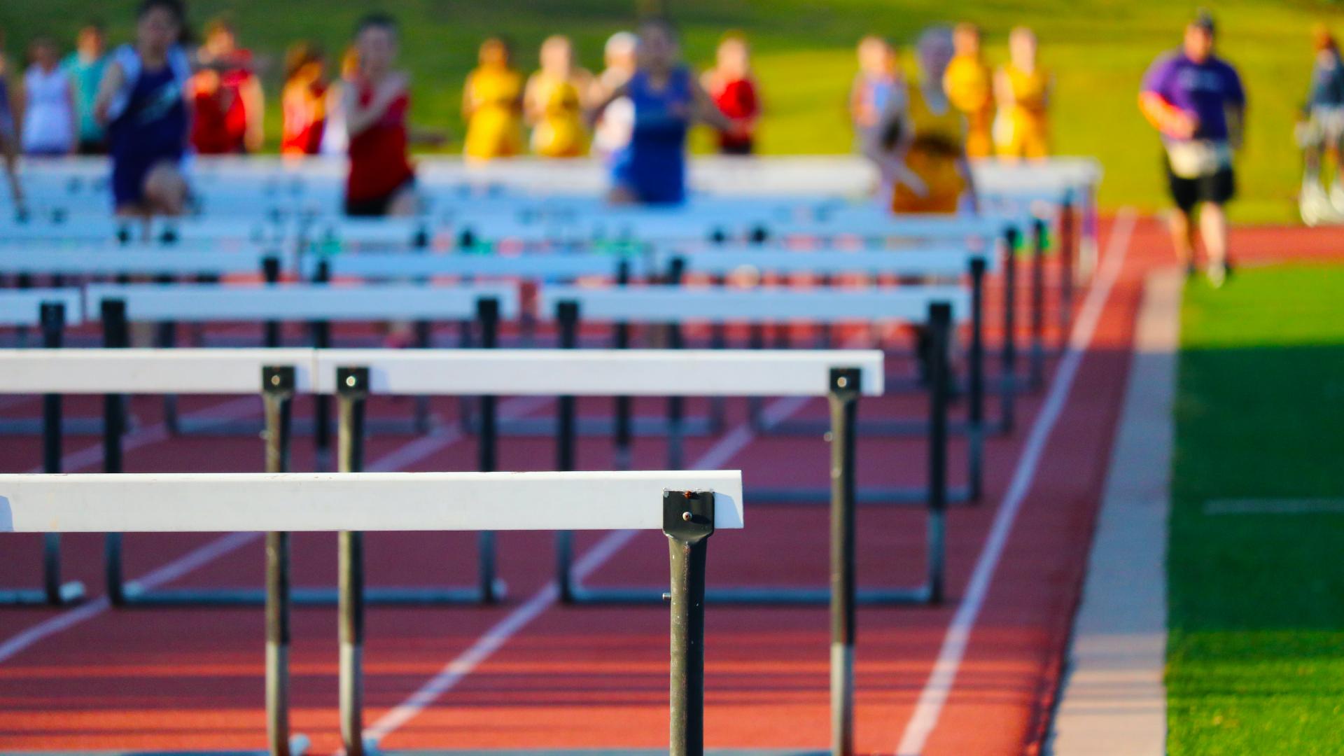 photo of people in a race jumping hurdles