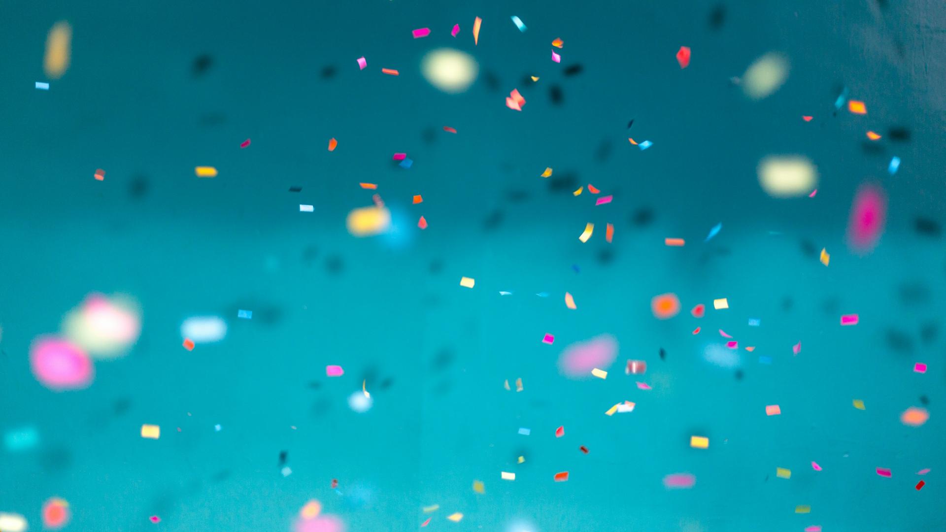 Colourful confetti falling down with a teal background