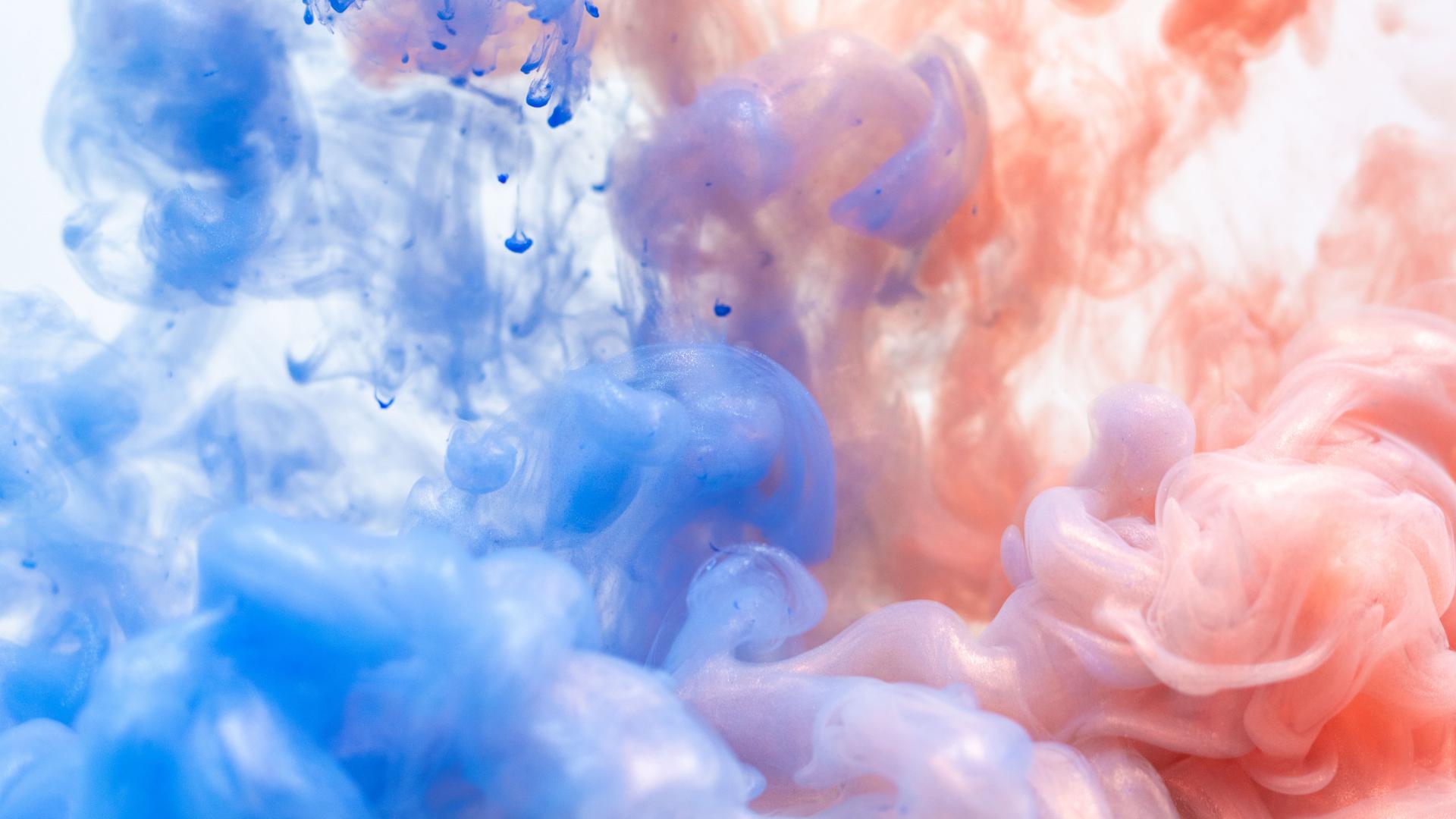 image of watercolour paint splashed into water, blue on left side red on right side