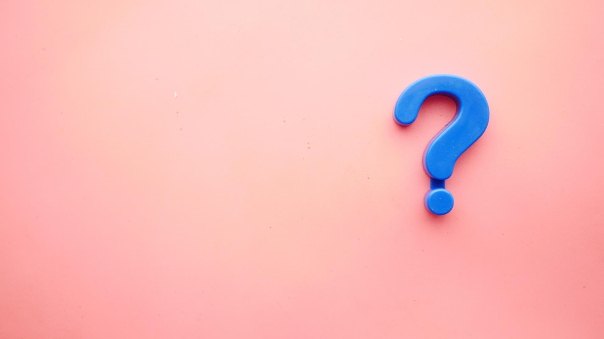 A blue question mark fridge magnet on a pink background